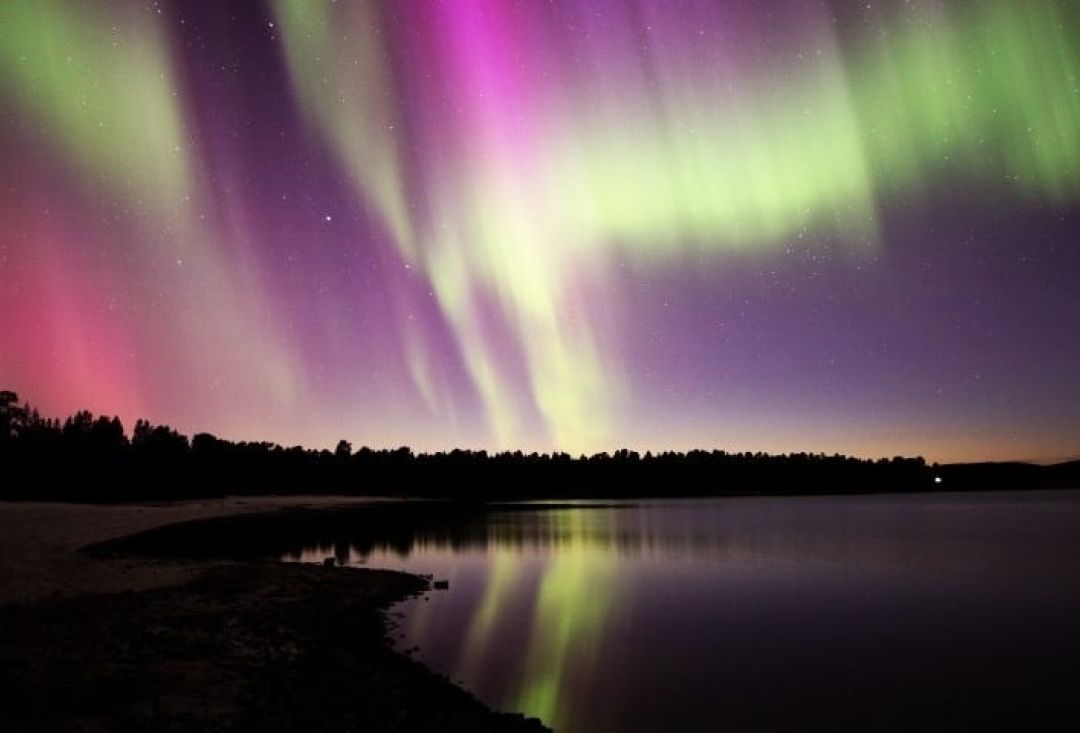 Erittäin kirkkaat ja värikkäät revontulet järven yllä .Kuva Pekka Aikio.