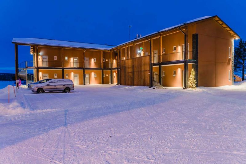 Hotelli Inarin rakennus talvi-iltana ulkoa kuvattuna. Paljon kauniita valoja seinillä.