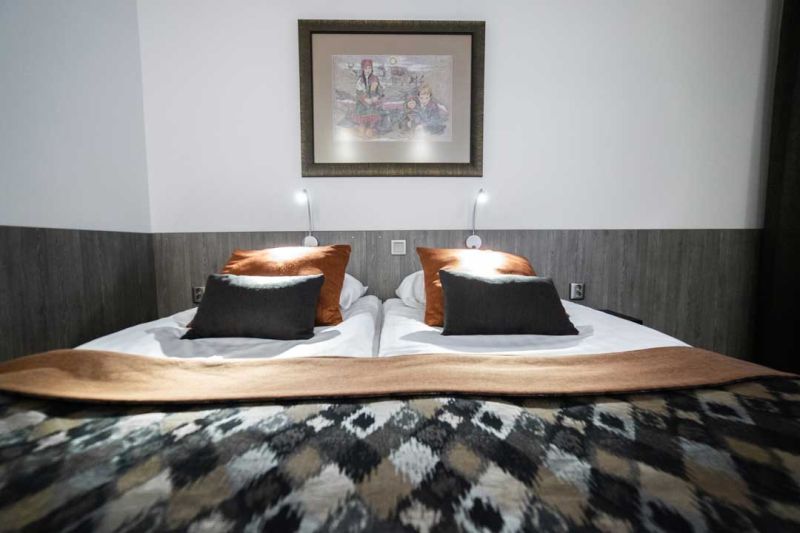 Parisänky tummilla tekstiileillä, harmailla puolipaneeleilla varustetussa makuuhuoneessa.