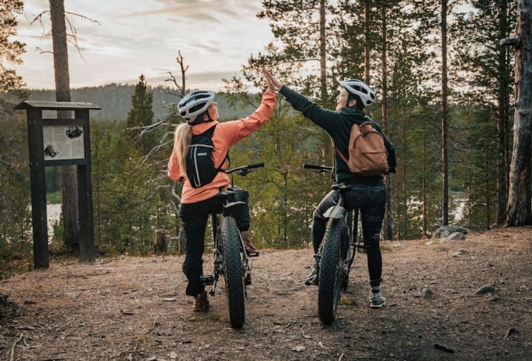Two bikers giving a five on top of hill in beautiful Lappish scenery.