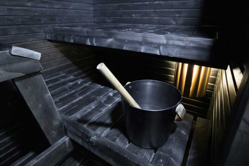 Musta sauna, keskimmäisellä lauteella kiulu kauhoineen.