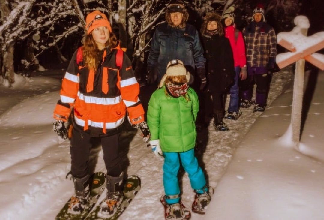 Group of people skiing in dark forest.