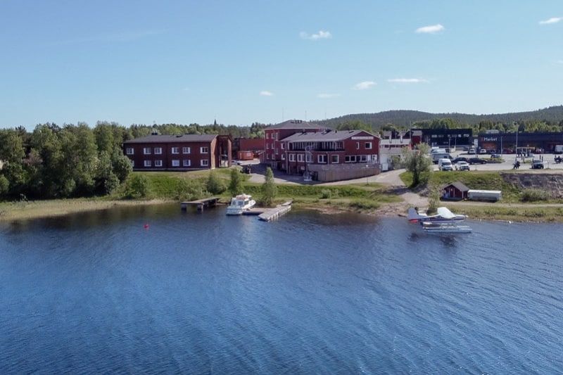 Järveltä otettu kuva hotellista, rannassa vene laiturissa ja vesitasokone.