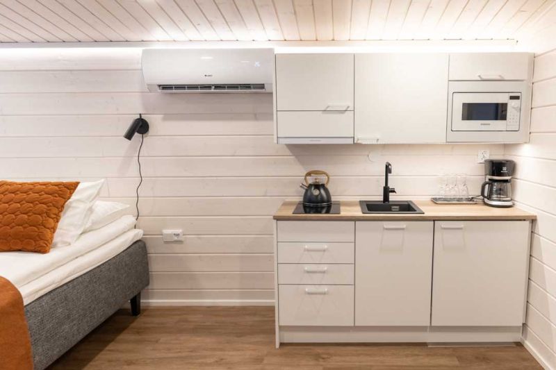 Kitchenette inside the studio cabin with white cabinets, sink and appliances