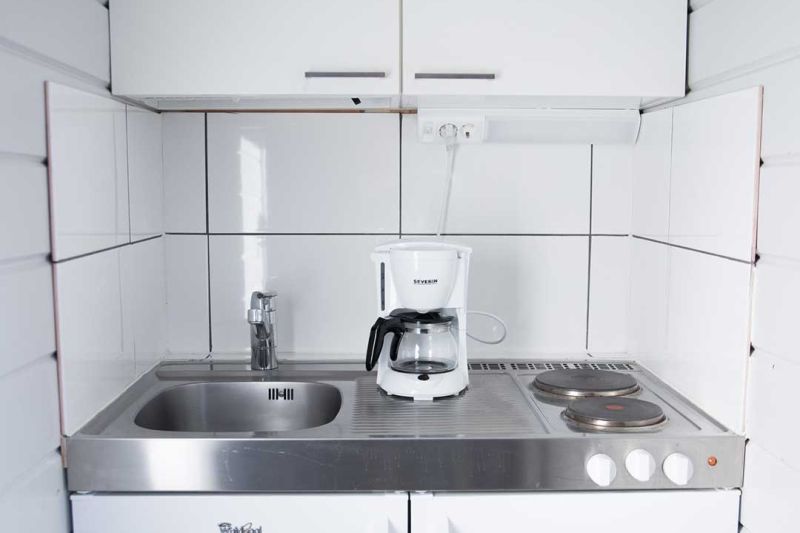 Keittonurkkaus, jossa tiskiallas, kahvinkeitin ja kaksi keittolevyä.