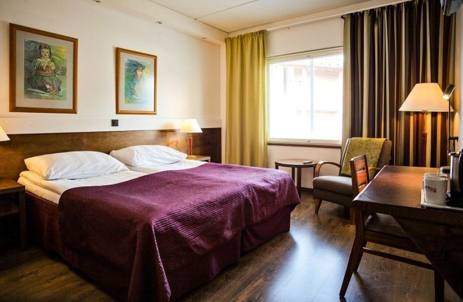 Huone parisängyllä, nojatuolilla ja pienellä ruokapöydällä.