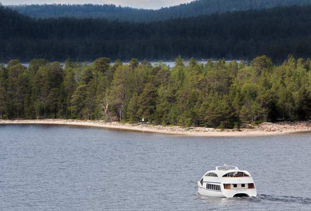 Inarinjärven risteilyalus matkaa järvellä ohittaen hiekkaista rantaa.