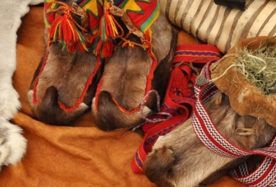 Pair of shoes made out of reindeer skin, decorated with colorful pieces of fabric.