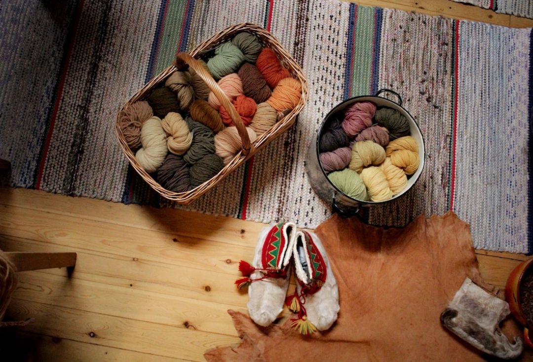 Beautifully colored wool threads in baskets on a floor rug.