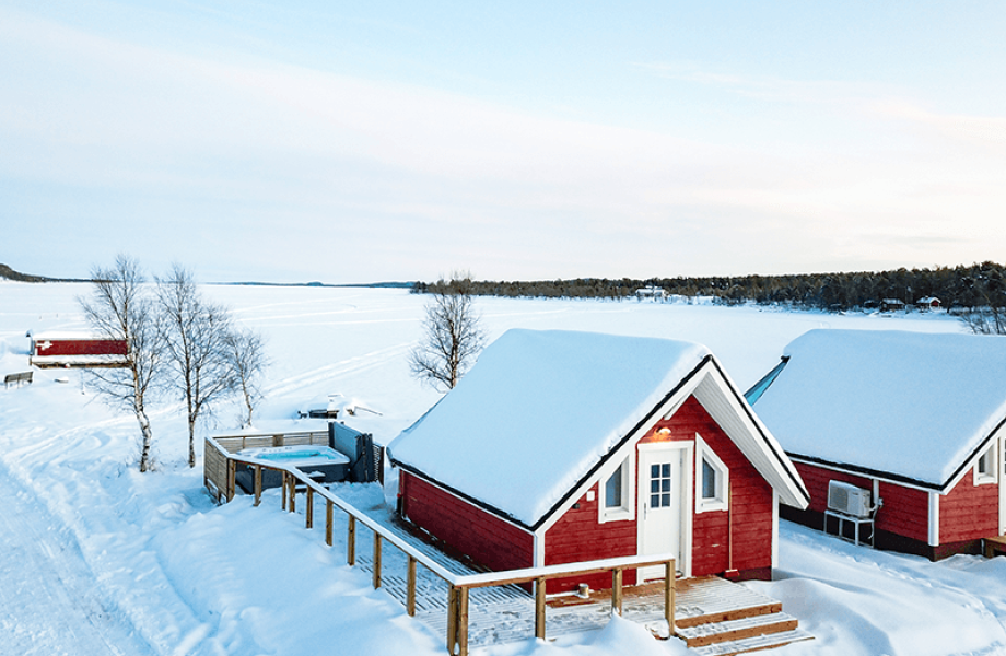 Aurora Sauna & Hot Spring ulkoapäin. Punainen mökki lumisessa maastossa.