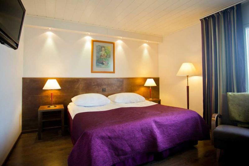 Parisänky yöpöydillä. Vieressä nojatuoli jota vastapäätä seinällä televisio.