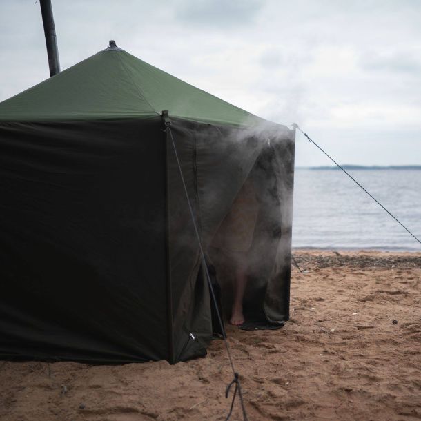 Saunateltta järven hiekkaisella rannalla. Savu nousee oviaukosta.