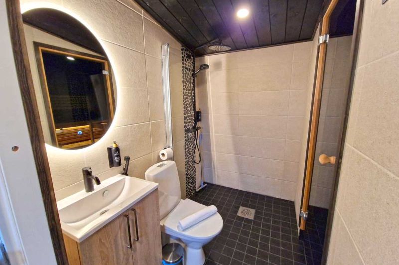 Spacious bathroom with sink, wc, round mirror and shower.