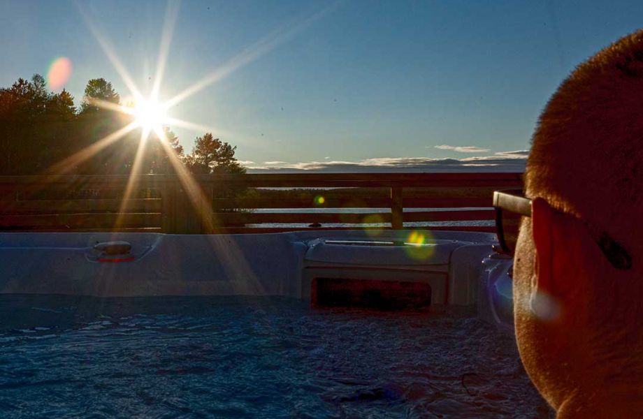 A person with sunglasses in a jacuzzi, sun is shining brightly.