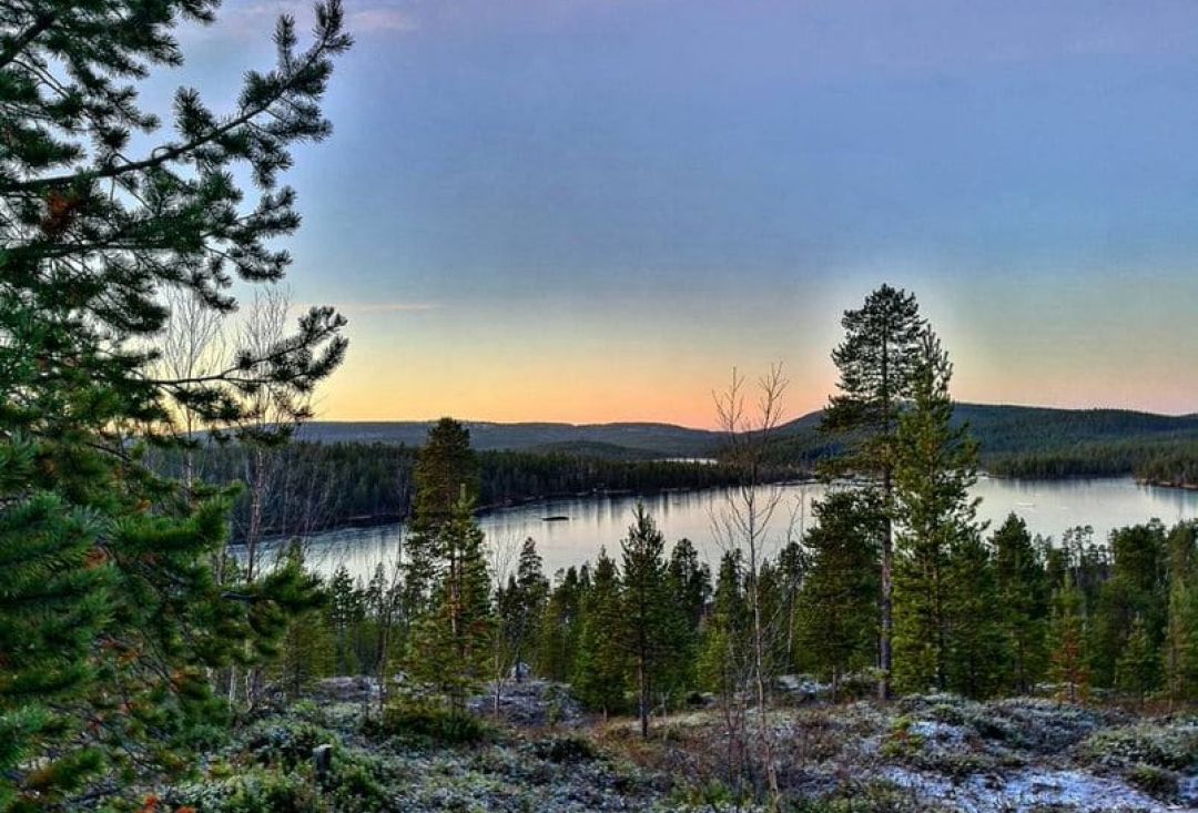 mäen päältä kuvattuna järvimaisemaa. Maassa kuuraa ja aurinko juuri nousemassa.