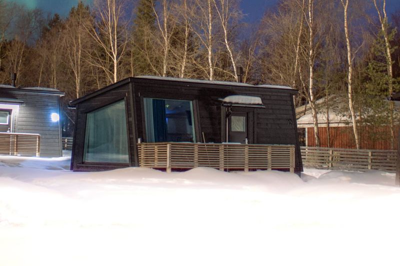Exterior of Scandinavian-style studio cabin with large window under northern sky