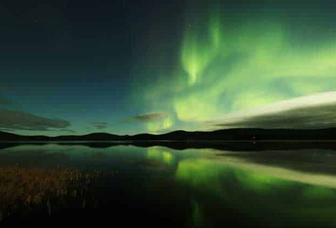 Lake on night with sky half covered with northern lights.