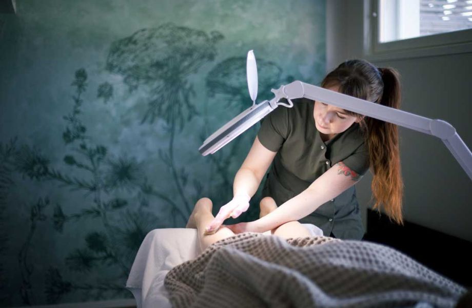 Hieroja hieroo pohjetta kohdevalon alla rauhallisessa huoneessa.