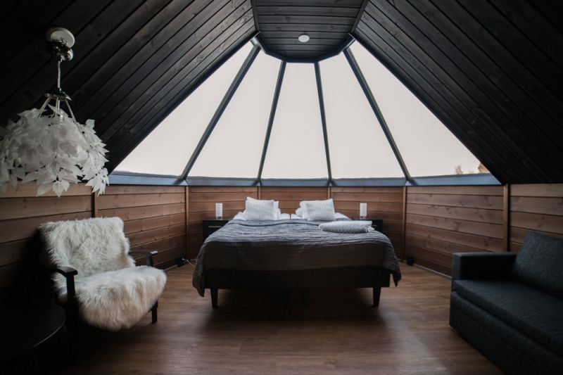 Cozy wood paneled room with dark ceiling. Comfortable twin bed and armchair with lamb skin.