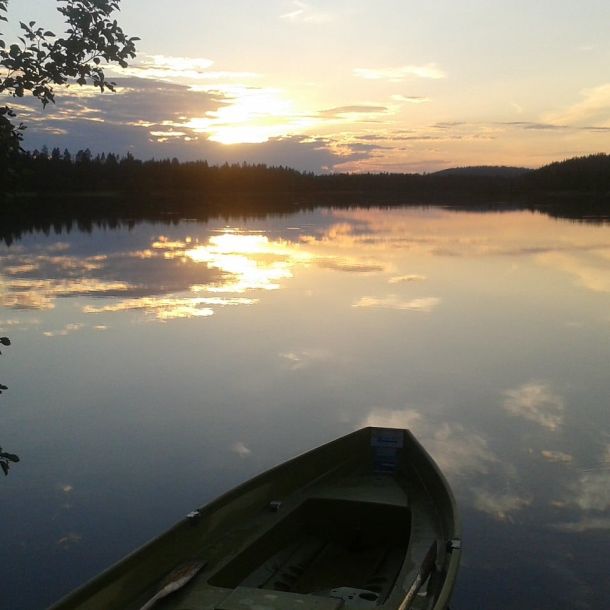 Soutuvene menossa tyynelle järvelle ilta-auringossa.