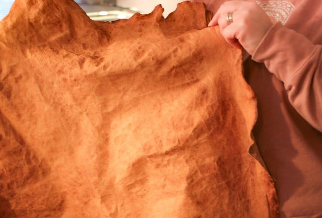 Henkilö pitelee suurta ryppyistä nahkanpalaa vierellään.