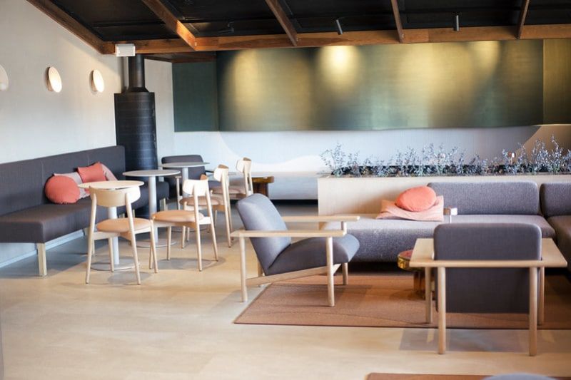 Hotelli Inarin oleskelualue, jossa sohvia, nojatuoleja ja moderni uuni nurkassa.