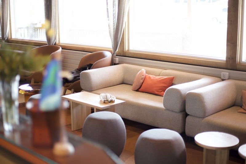 Oleskelualue moderneilla, vaaleilla sohvilla. Isot ikkunat taustalla.