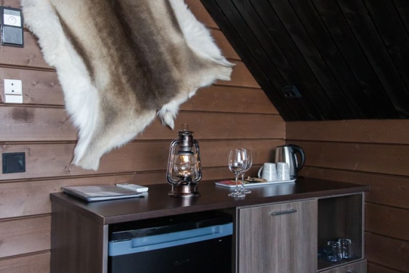Wood patterned unit with black fridge. Above is a reindeer skin on the wall.