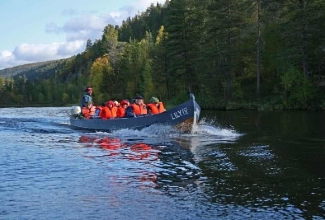Group of people sitting in a boat with life jackets on. Boat traveling fast ahead.