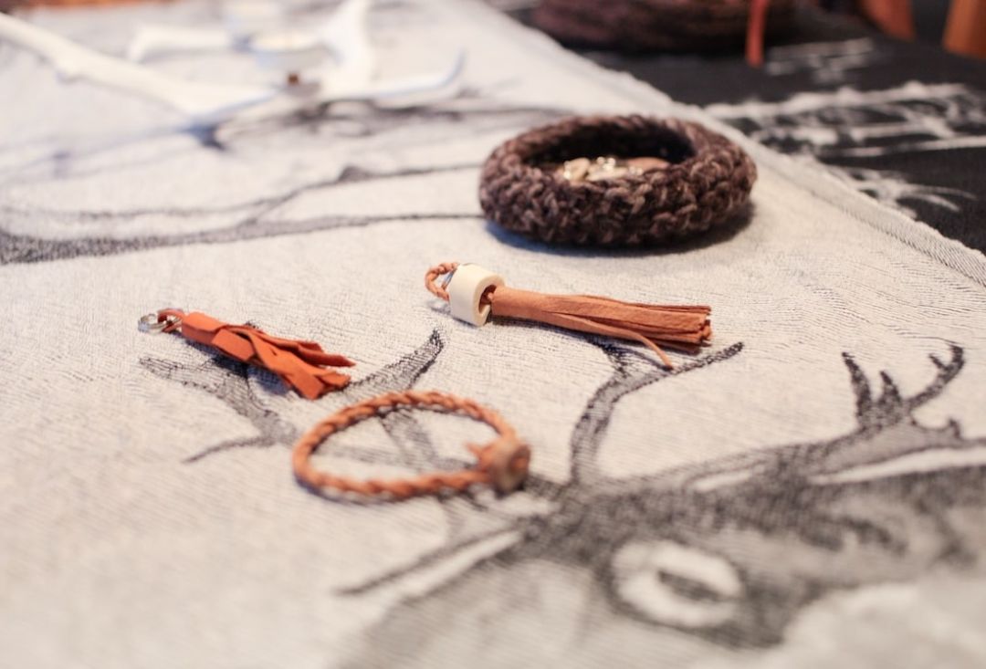 Valmiita nahkaisia tupsuja ja rannerenkaita porokuvioidun pöytäliinan päällä. Kuva Miika Leivo