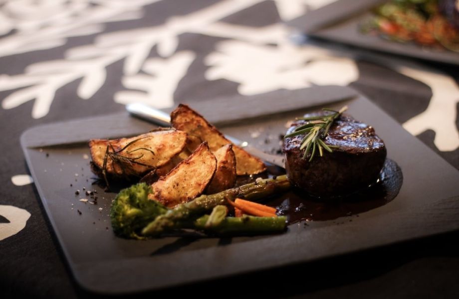 Restaurant Auroras dish in plate. Dish includes round meat piece, potato chip and asparagus.