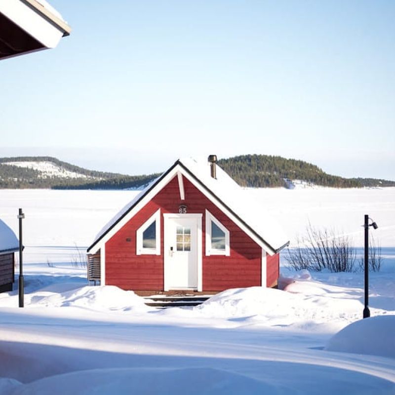 Holiday Village Inari cabin in snowy view by the lake.